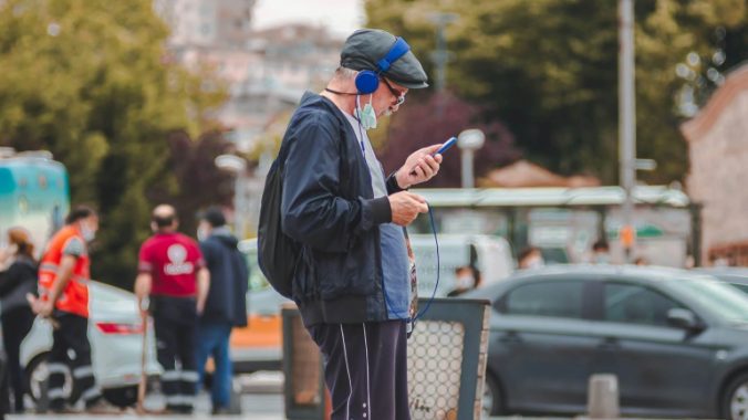 Un hombre mayor con auriculares y escuchando un podcast en su teléfono